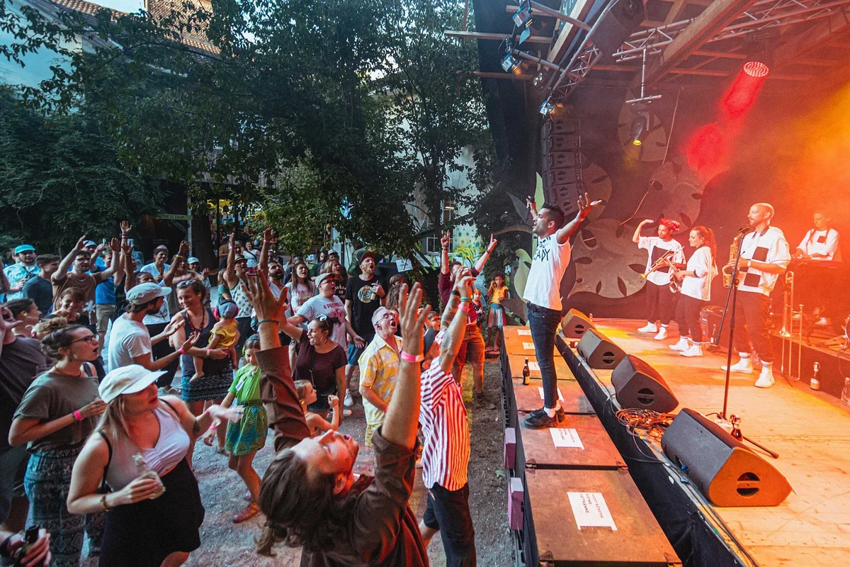Man sieht eine Openair-Bühne mit vielen Zuschauern.
